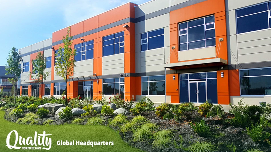 An orange and gray two-story office building, with grass, plants, trees and rocks in front of it under a blue sky. White text at the bottom of the photo reads Quality Horticulture Global Headquarters.