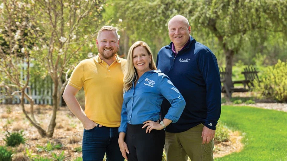 Three smiling people pose for a photo.